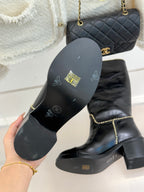 Black boot sole with embossed markings, with knee-high boot beside it