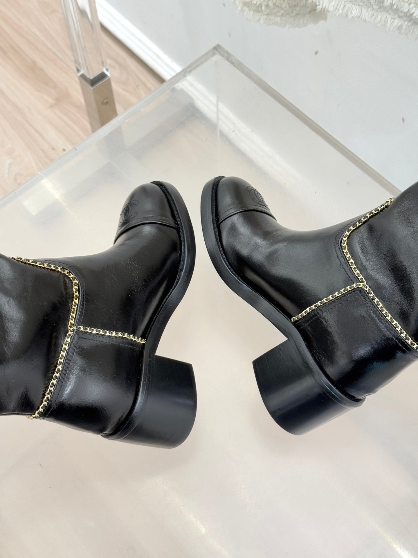 Black knee-high boots with gold chain trim, showing heel and rounded toe