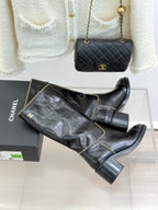 Black knee-high boots with gold chain trim, side angle view