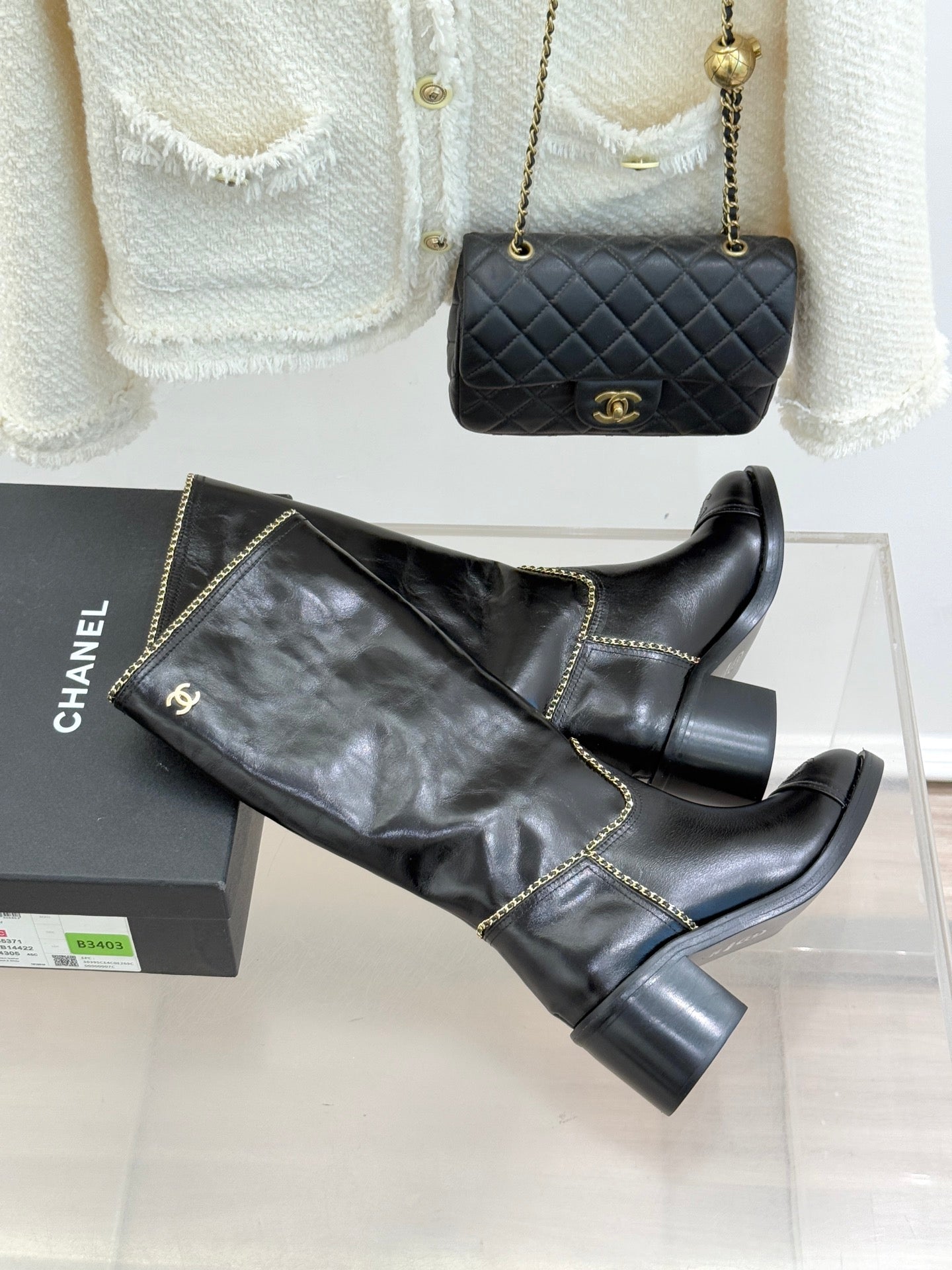 Black knee-high boots with gold chain trim, side angle view