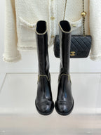 Front view of black knee-high boots with gold chain trim and round toe