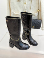 Two black knee-high boots with gold chain trim and stacked block heel