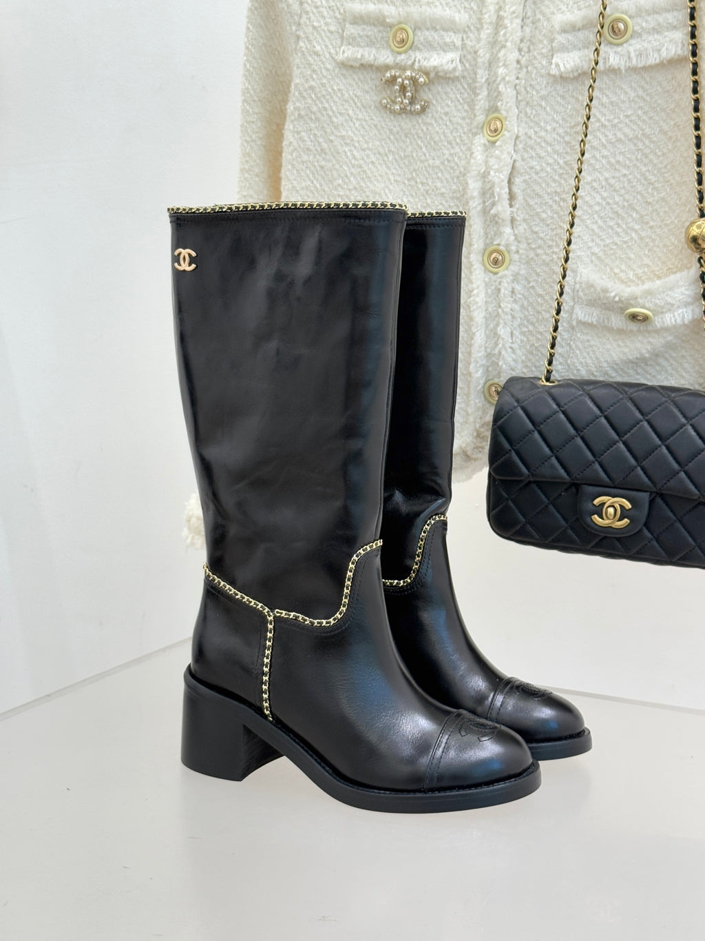 Black knee-high leather boots with gold chain trim and block heel