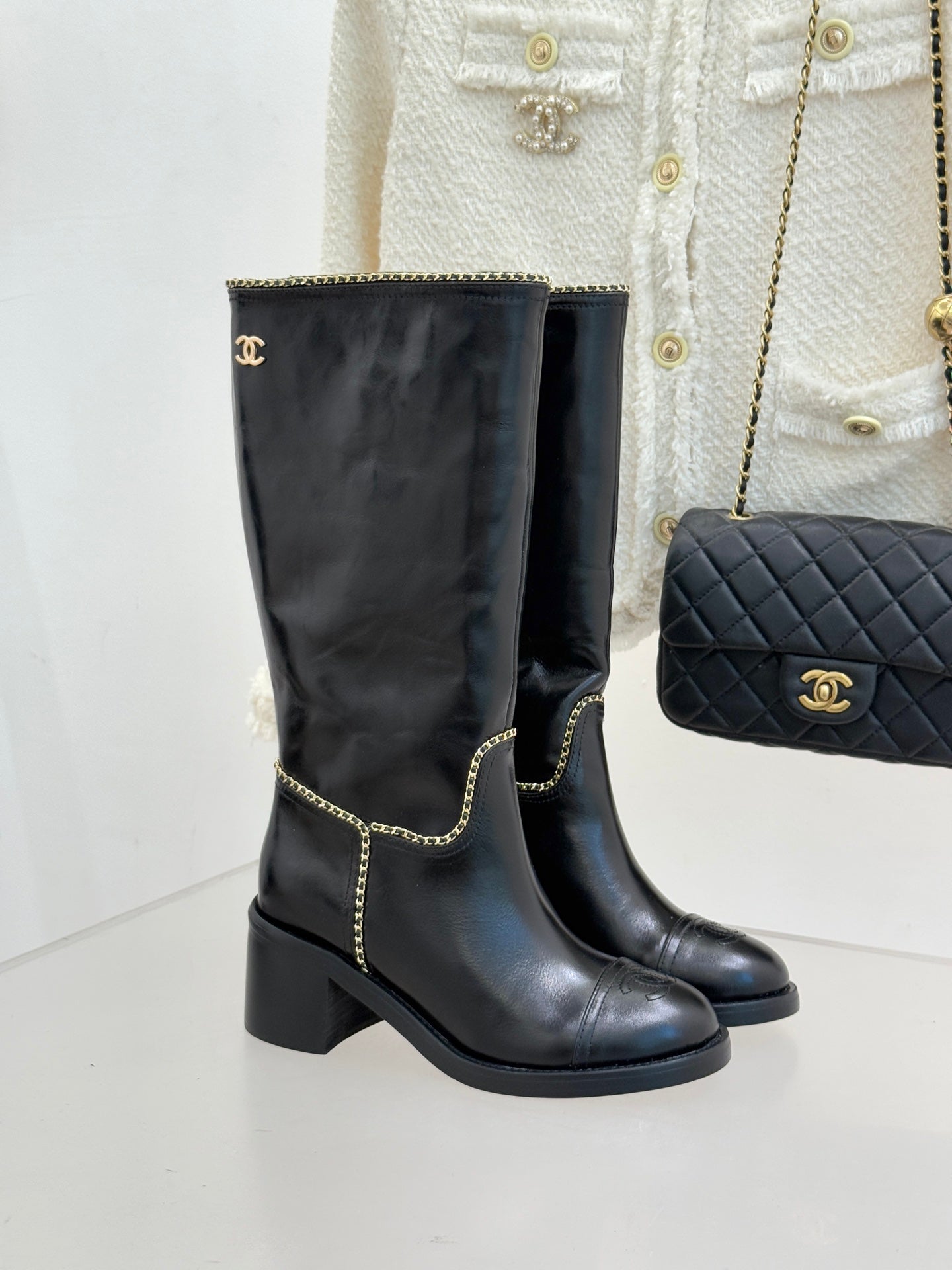 Black knee-high leather boots with gold chain trim and block heel