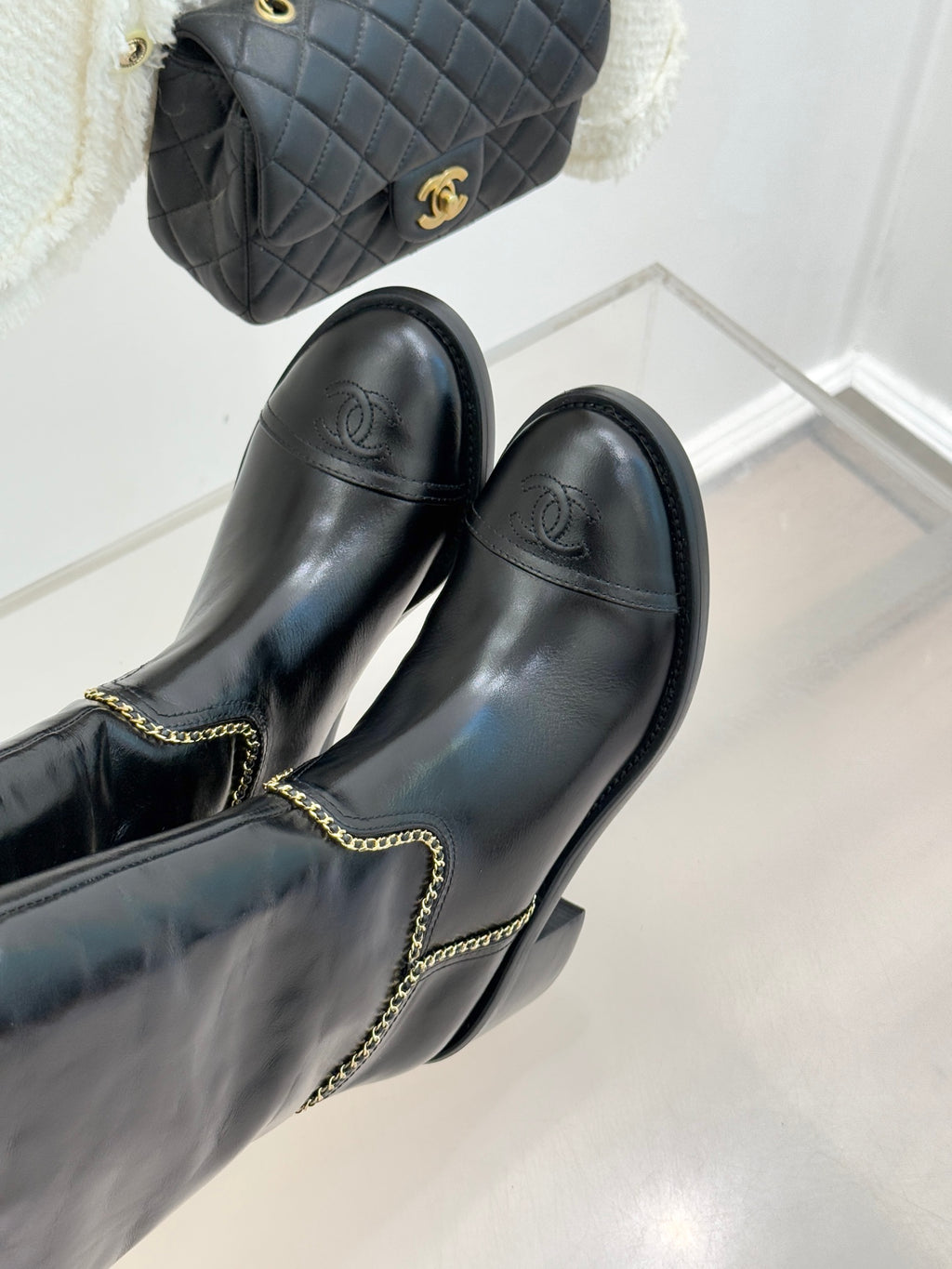 Side view of black knee-high boots with gold chain trim and block heel