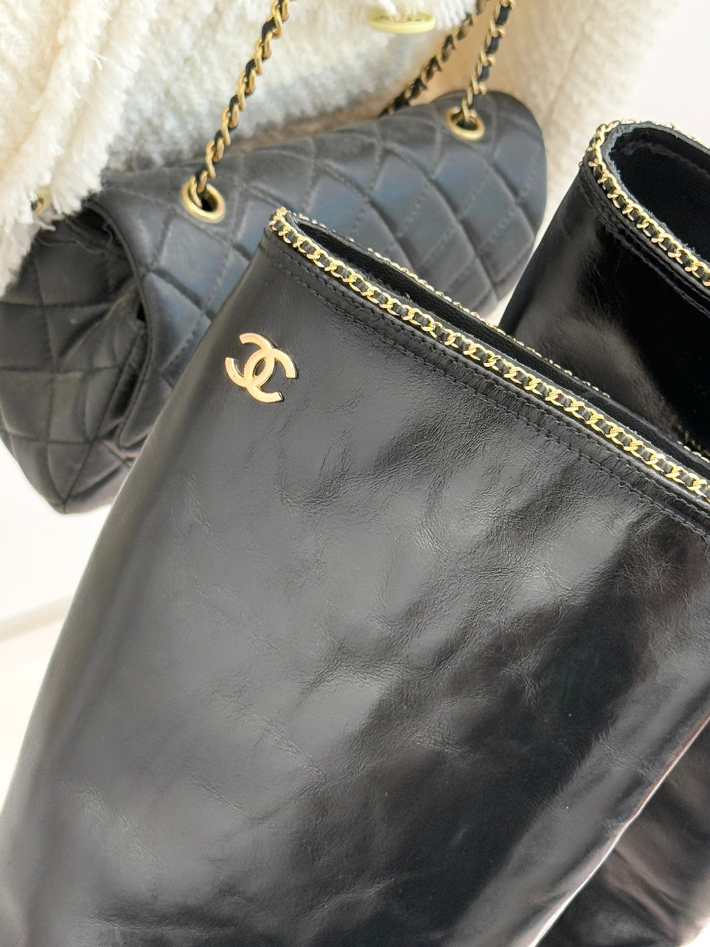 Close-up of black leather boot upper with gold chain trim and emblem