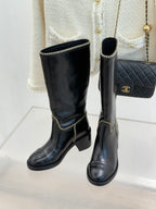 Pair of black knee-high boots with gold chain trim and low block heel