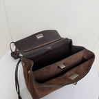 Brown suede handbag open interior with black lining and metal clasp hardware.