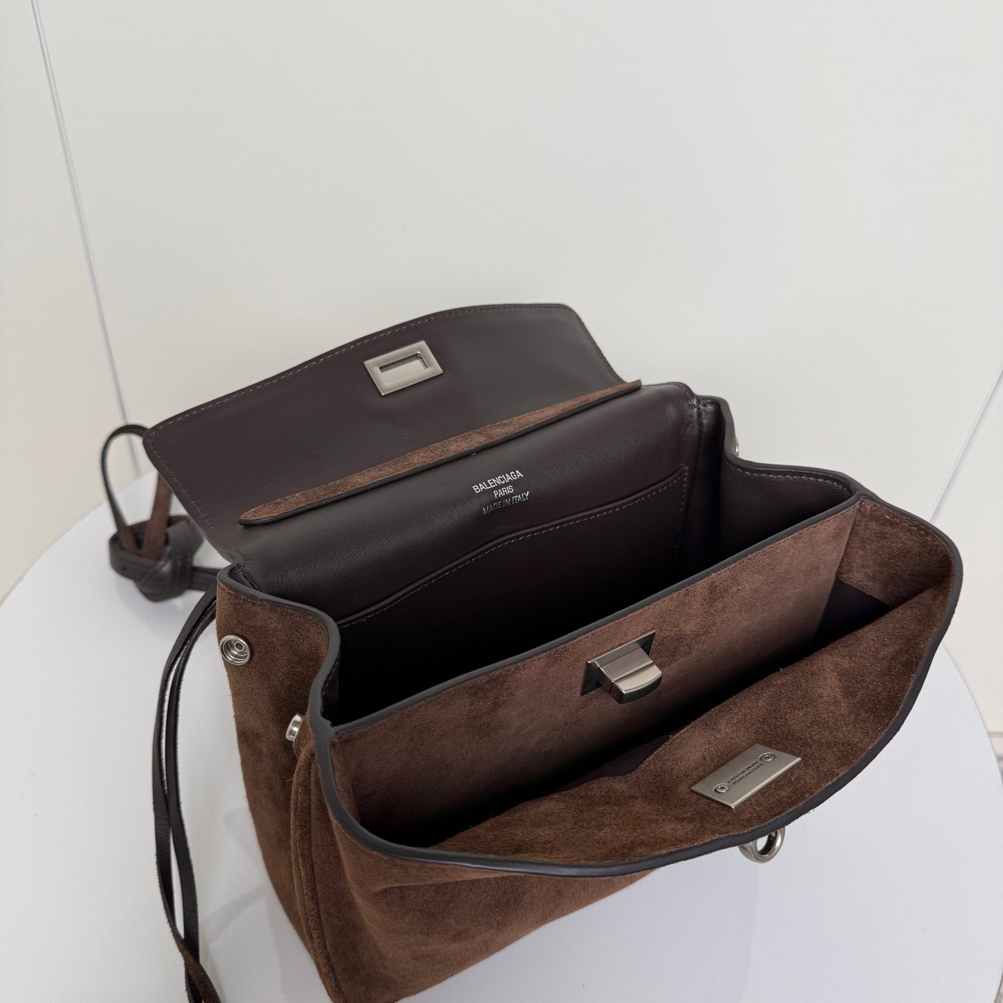 Brown suede handbag open interior with black lining and metal clasp hardware.