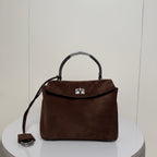 Brown suede handbag with single top handle and front clasp, shoulder strap attached.