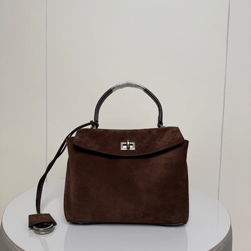 Brown suede handbag with single top handle and front clasp, shoulder strap attached.