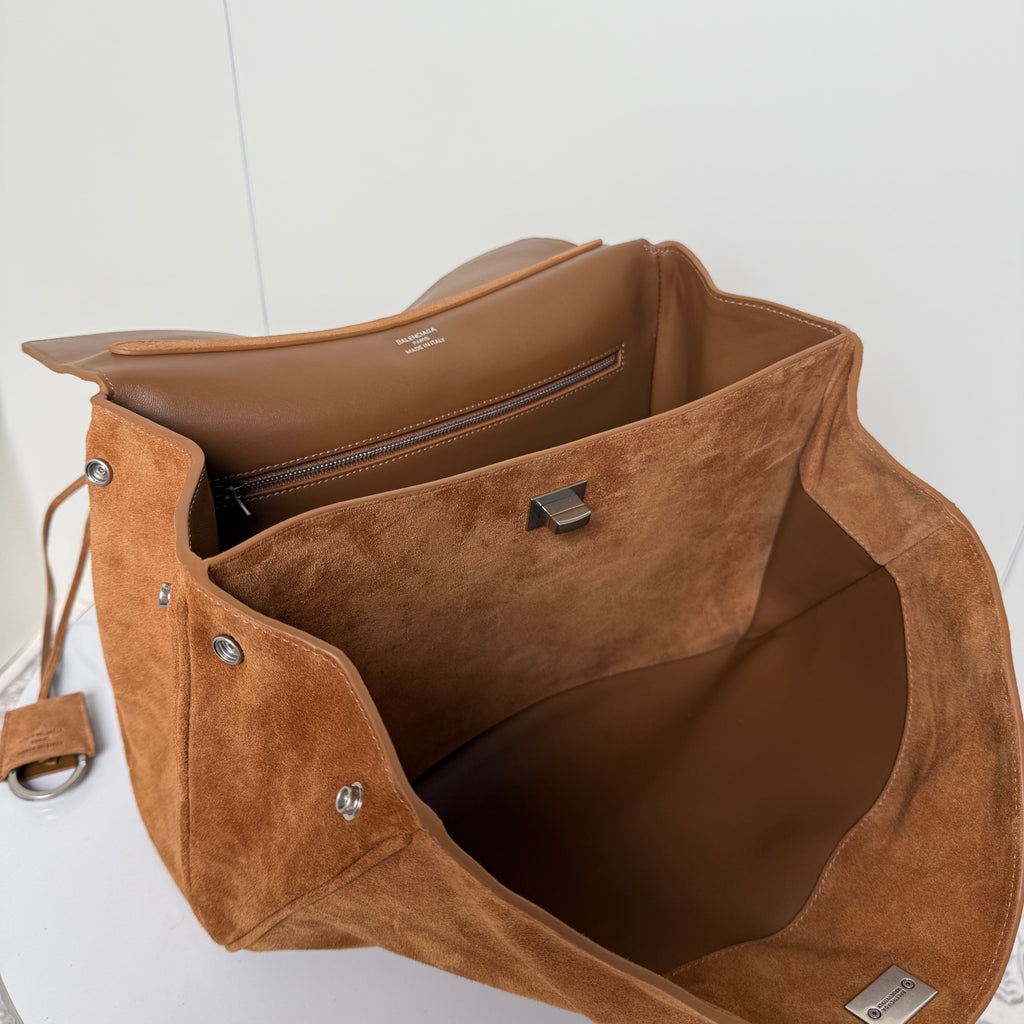 Open tan suede handbag with brown leather lining, interior pocket, and metal clasp