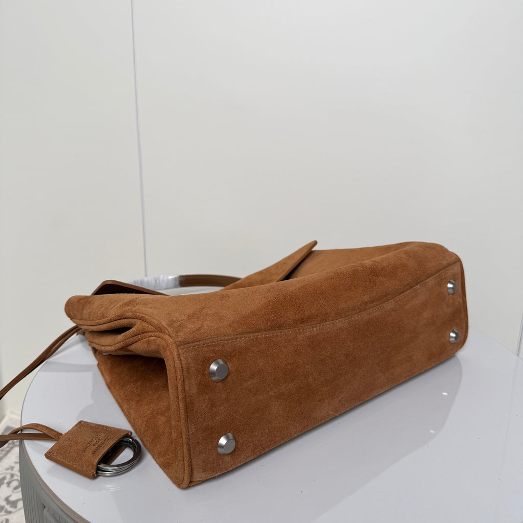 Tan suede handbag with bottom studs and leather handle straps