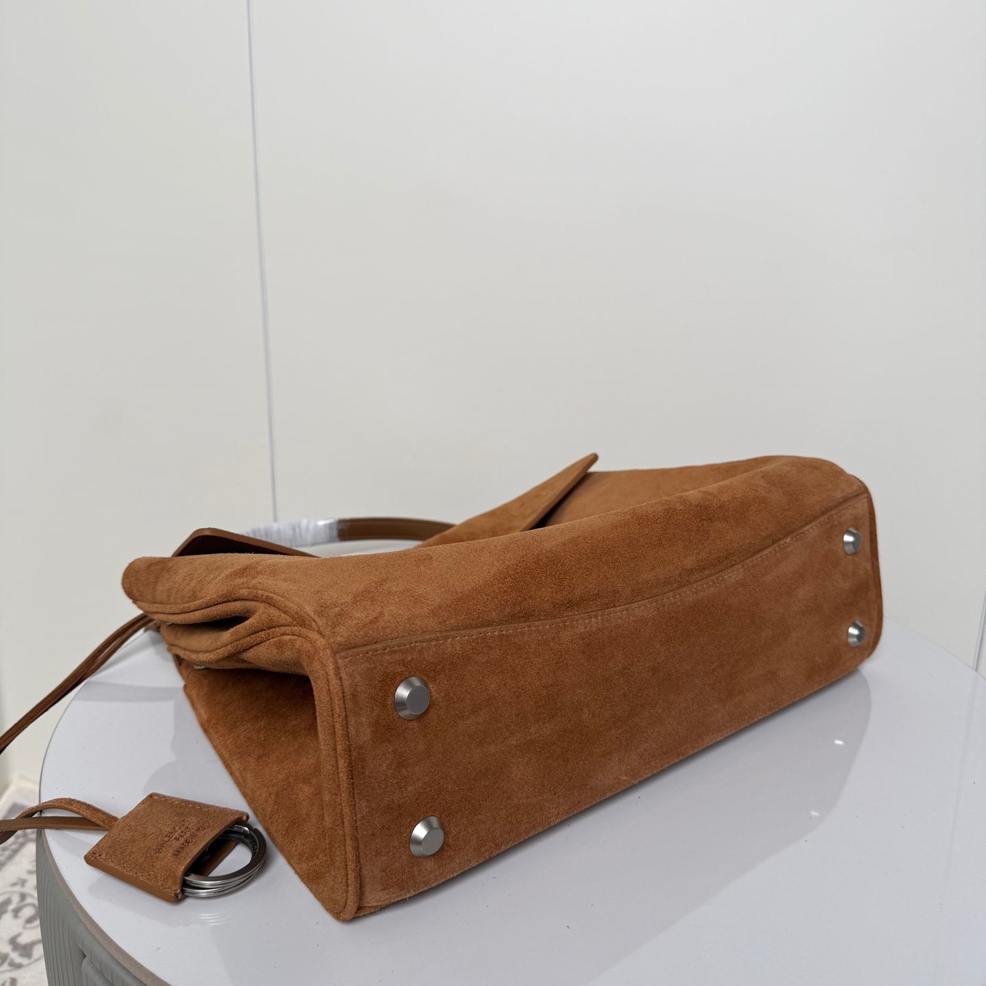 Tan suede handbag with bottom studs and leather handle straps