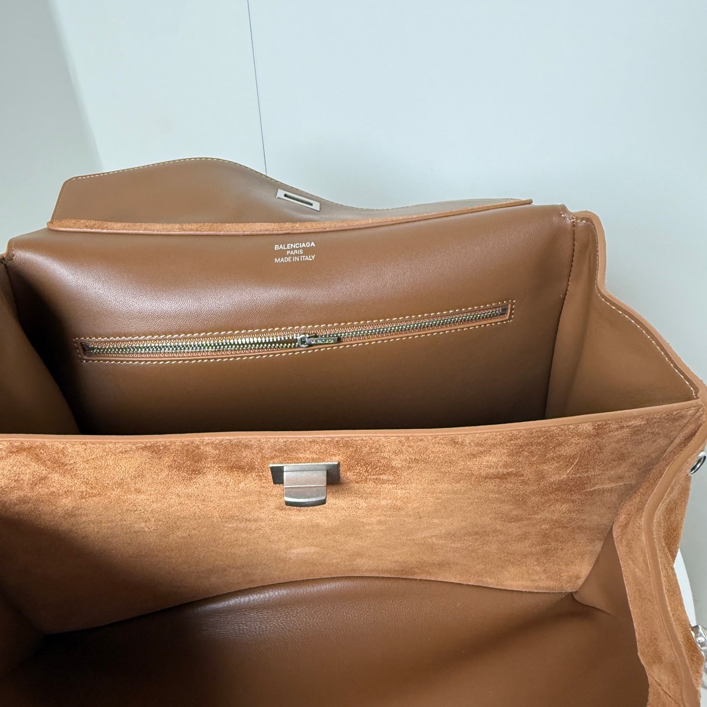 Tan suede handbag interior with brown lining, center latch, and zipper track