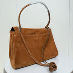 Tan suede handbag with top handle, crossbody strap, and front zippered pocket