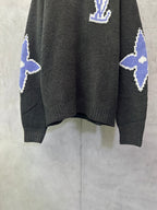 Dark charcoal knit sweater with blue-and-white diamond pattern on sleeves and hem