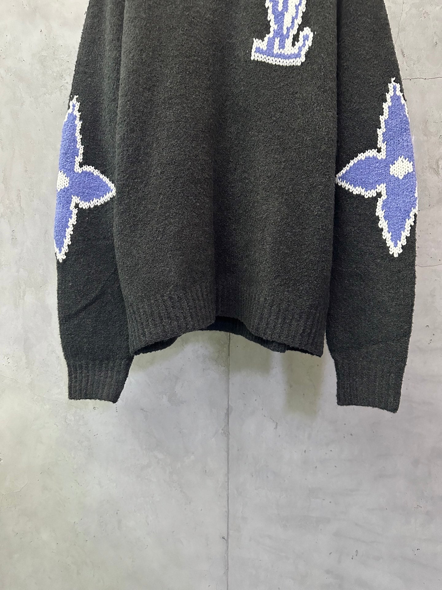 Dark charcoal knit sweater with blue-and-white diamond pattern on sleeves and hem