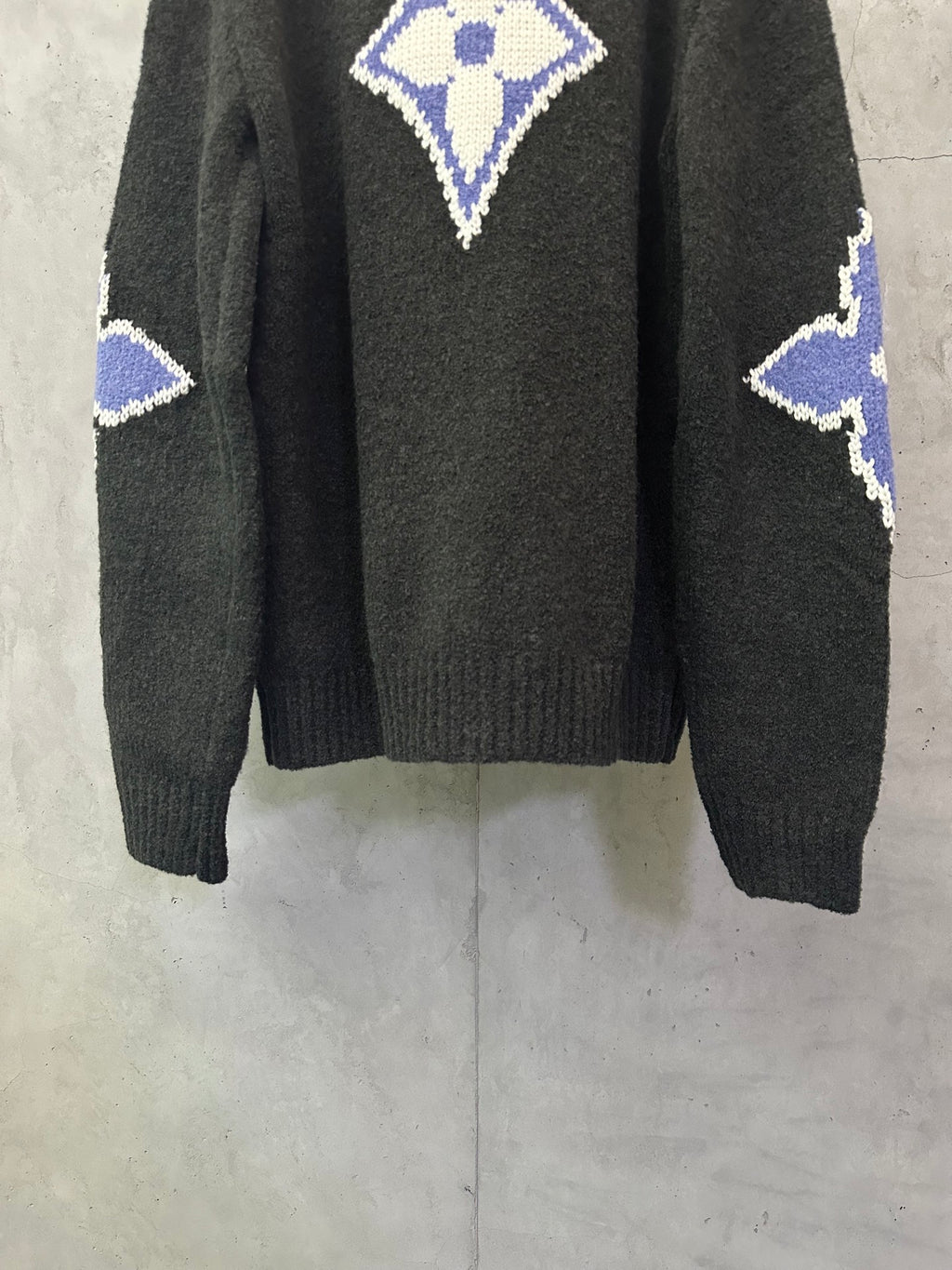 Dark charcoal knit sweater back view with blue-and-white monogram diamond and side motifs