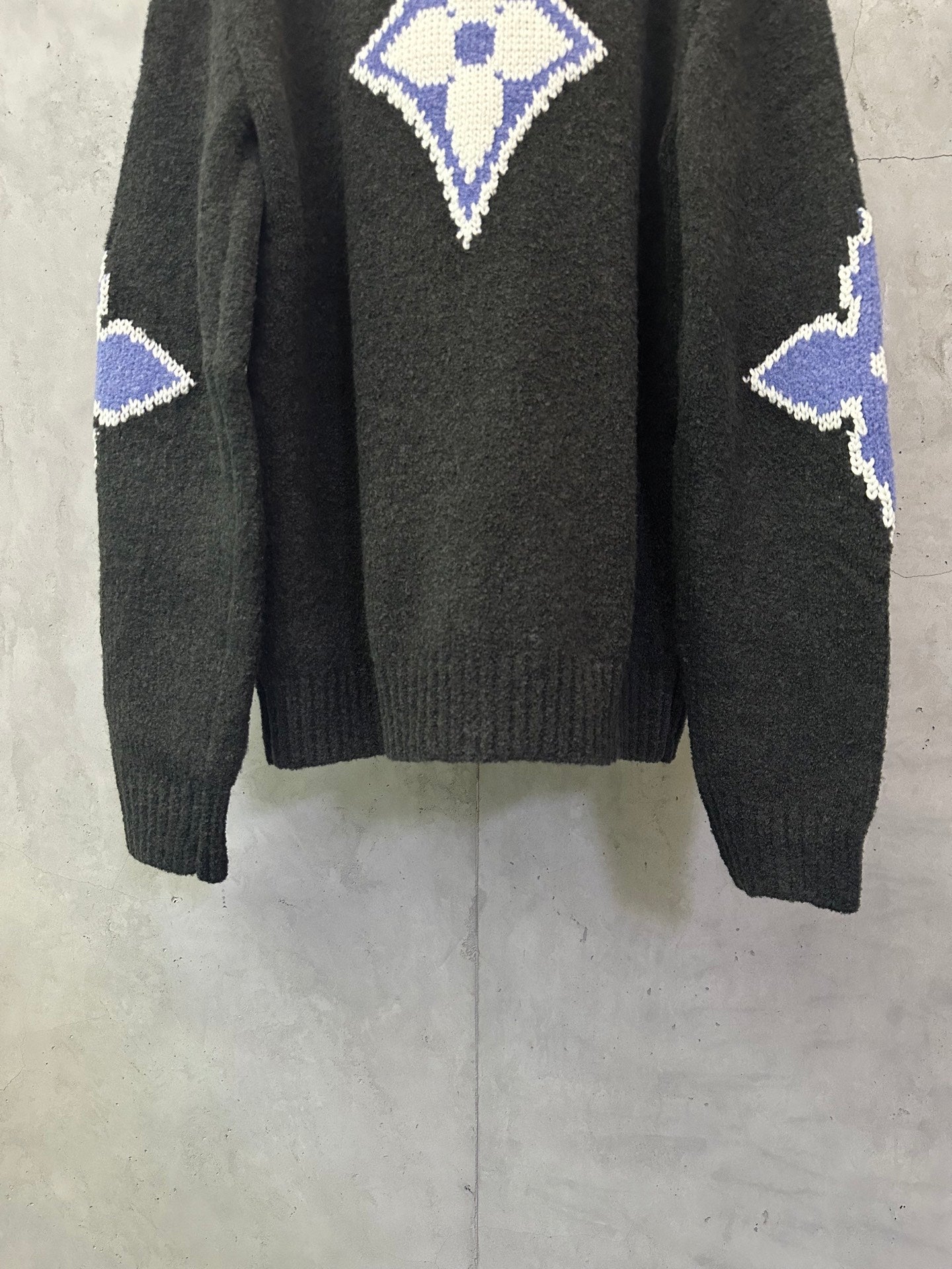 Dark charcoal knit sweater back view with blue-and-white monogram diamond and side motifs