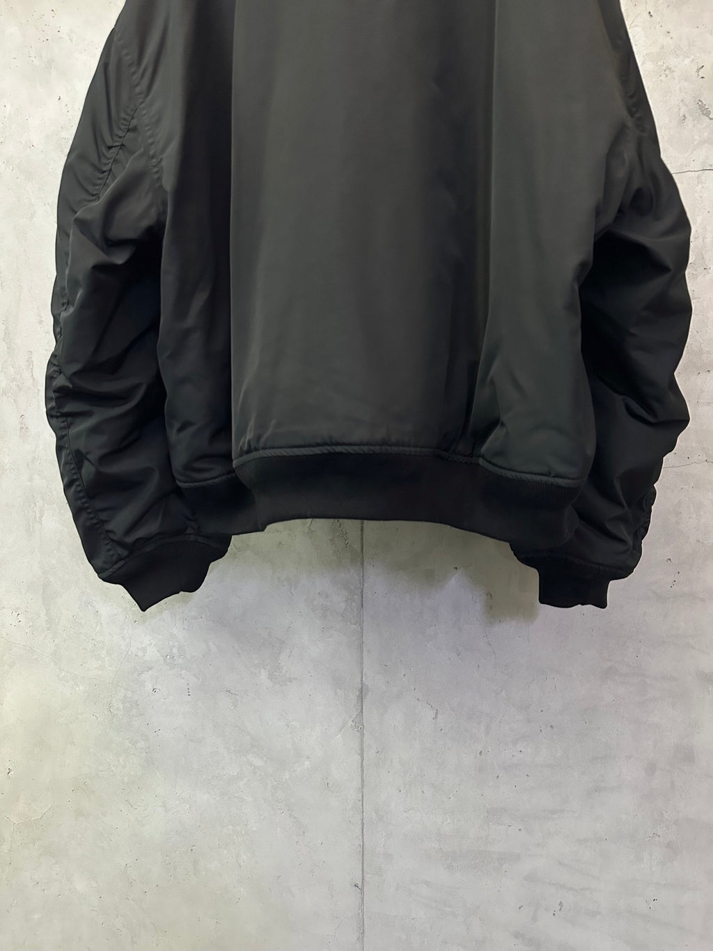 Black bomber jacket back view with ribbed hem and gathered sleeve cuffs