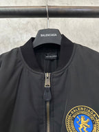Black bomber jacket with stand collar, zip pull, and BALENCIAGA crest patch
