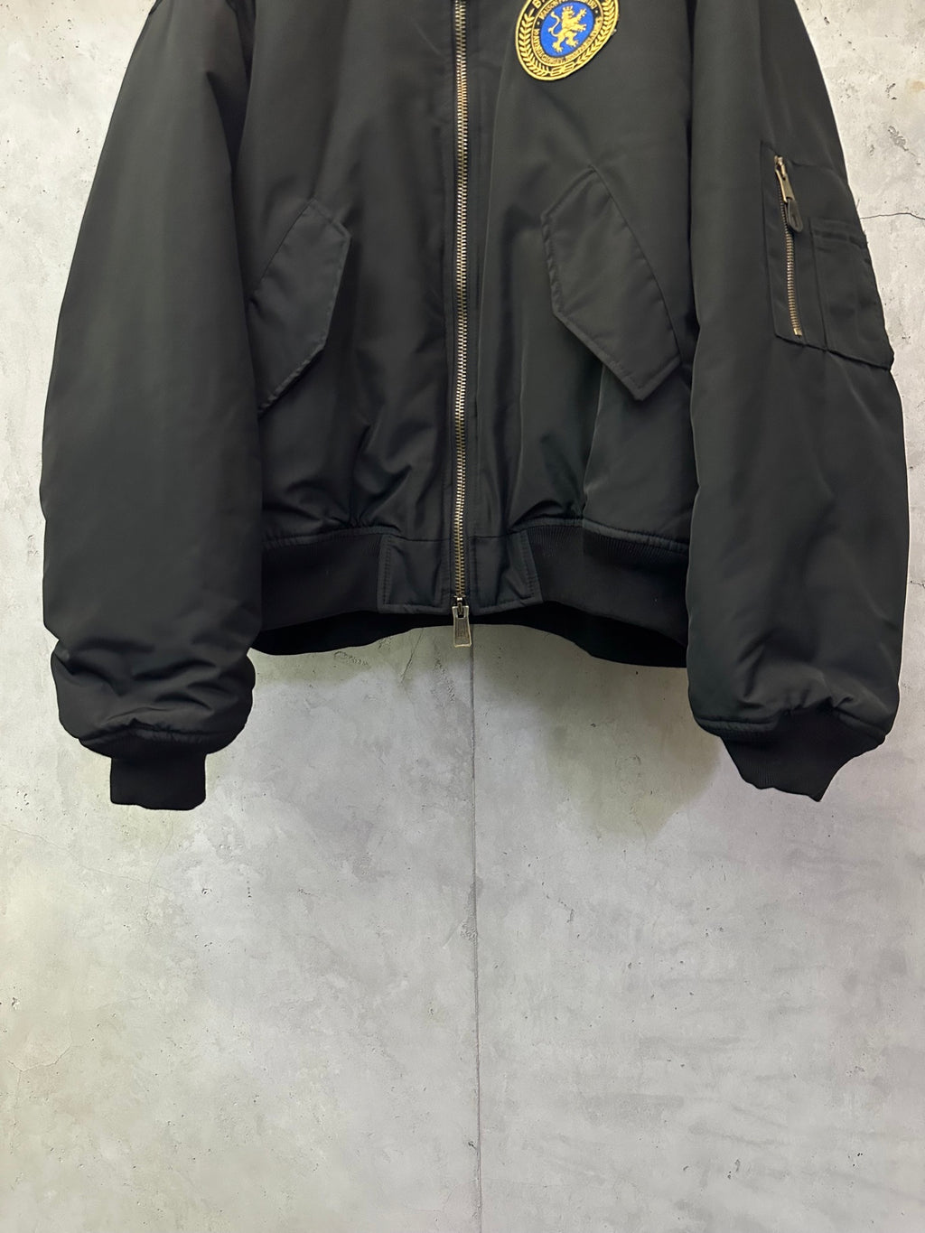 Black bomber jacket with zip front, flap pockets, and ribbed waistband