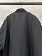 Black bomber jacket back view with ribbed hem and smooth fabric finish