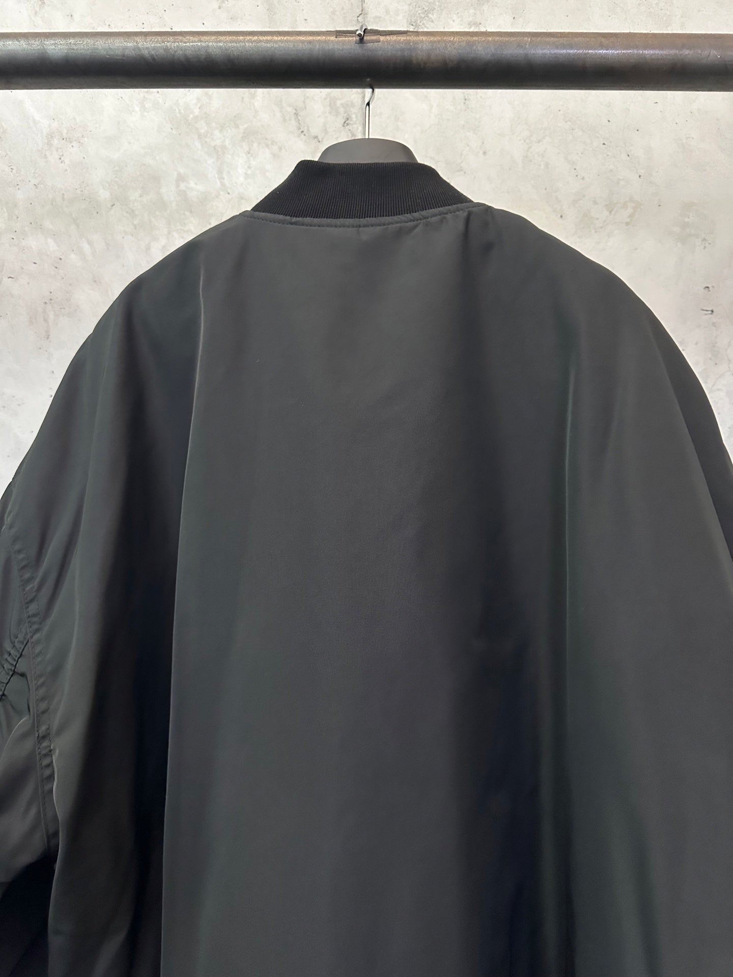 Black bomber jacket back view with ribbed hem and smooth fabric finish