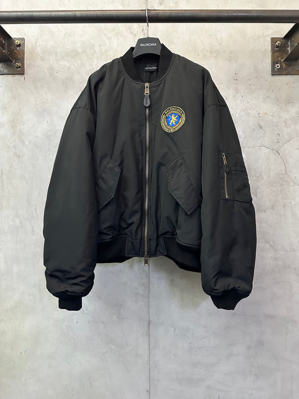 Black bomber jacket with zip front and BALENCIAGA crest patch on chest