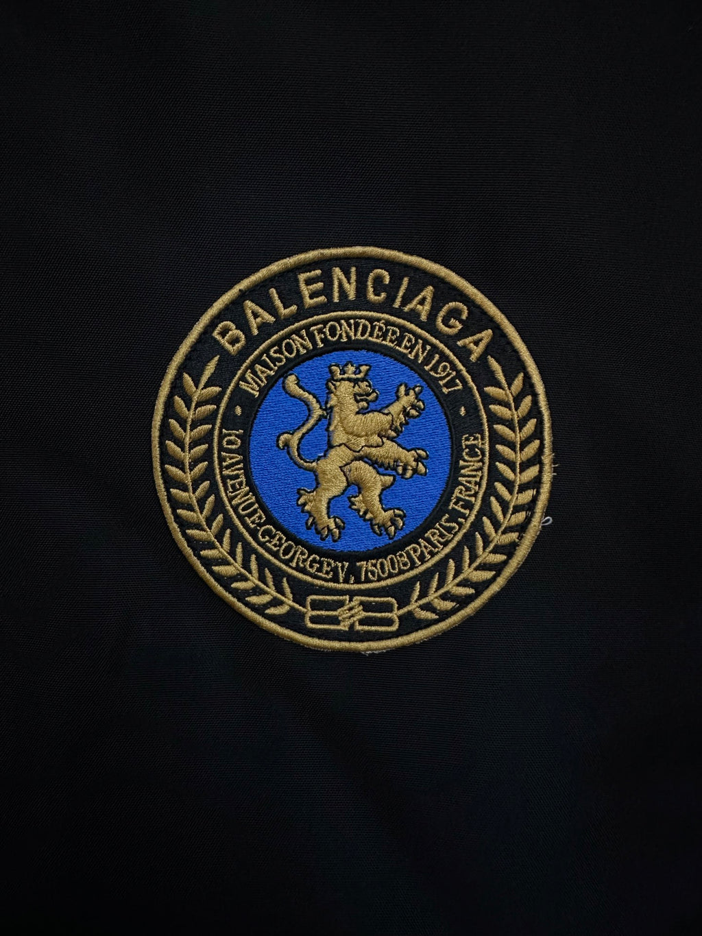 BALENCIAGA gold-and-blue crest patch embroidered on black fabric