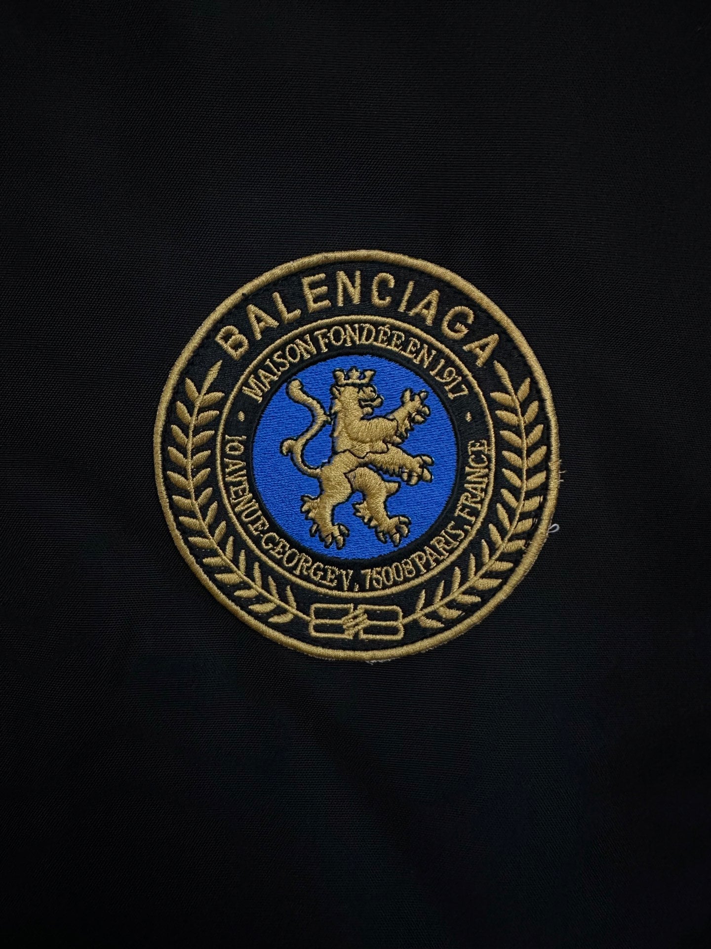 BALENCIAGA gold-and-blue crest patch embroidered on black fabric