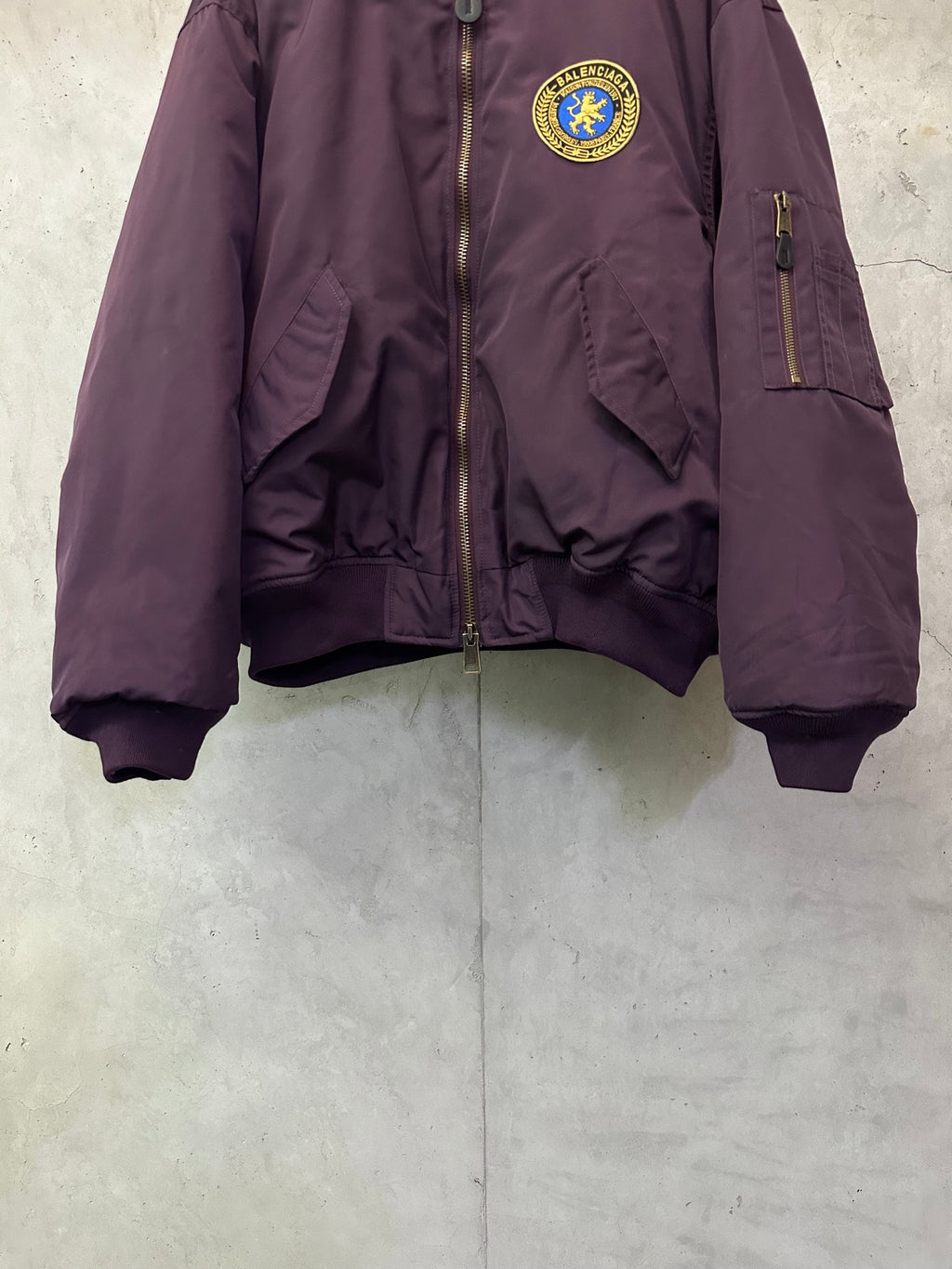 Purple zip bomber jacket with crest logo patch, side pockets, and ribbed cuffs
