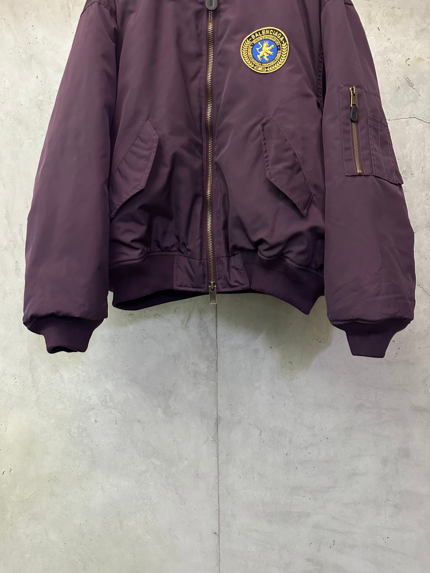 Purple zip bomber jacket with crest logo patch, side pockets, and ribbed cuffs