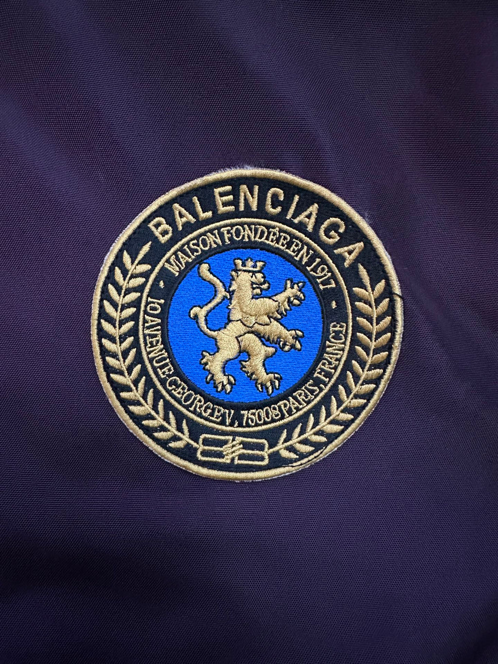 Embroidered crest logo patch on purple bomber jacket with blue lion