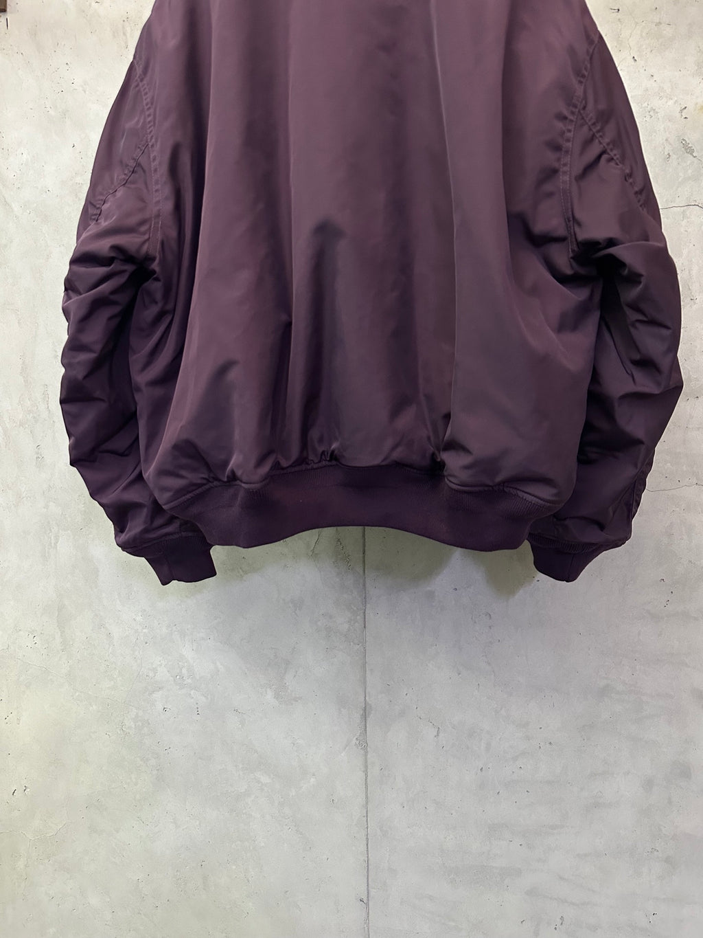 Purple bomber jacket back with ribbed hem and gathered fabric at sleeves
