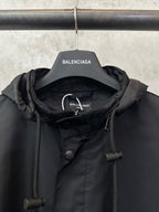 Black jacket neckline with hood, button placket, and drawcord toggles