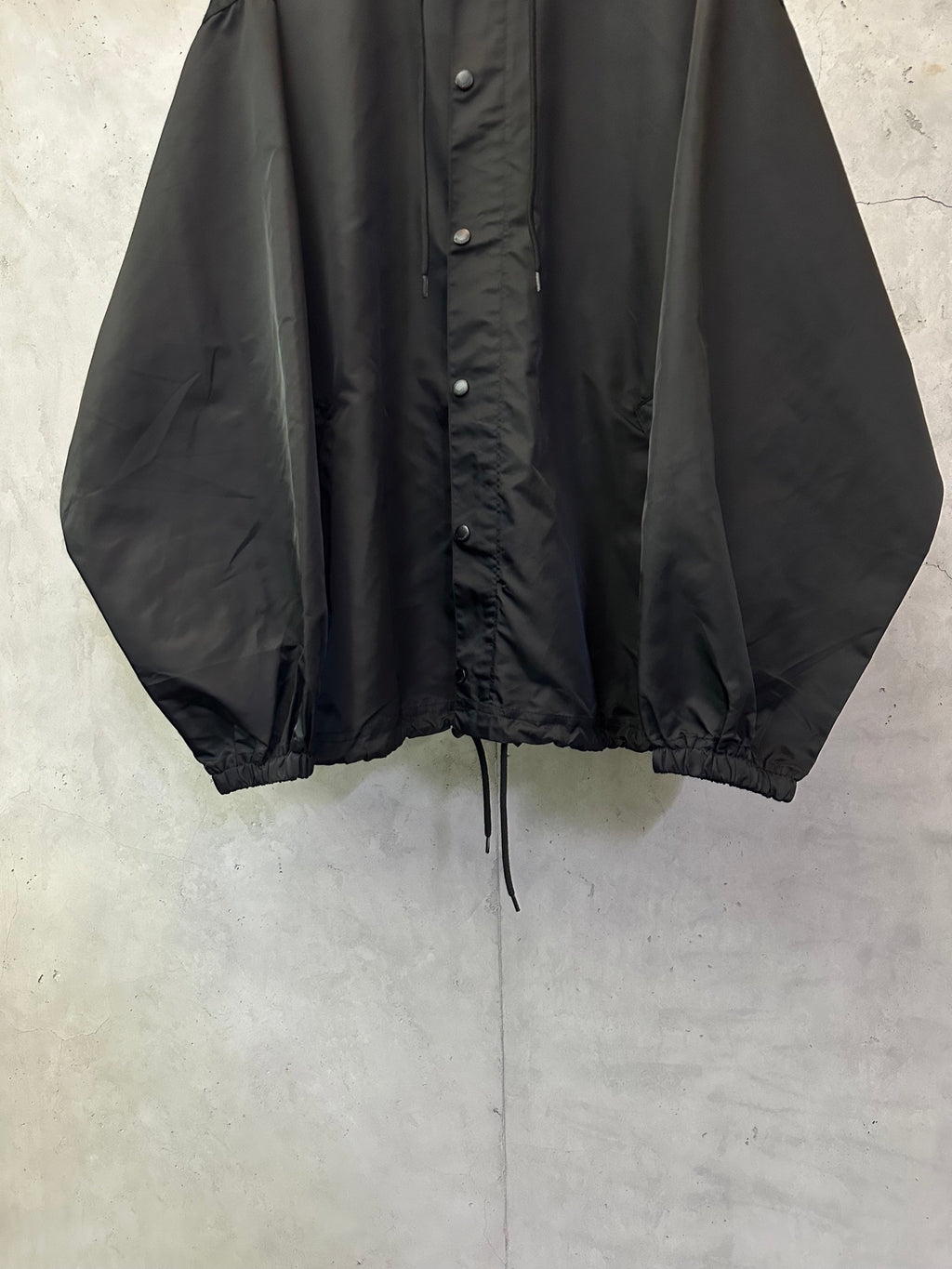 Black hooded jacket front view with button placket and drawstring waist