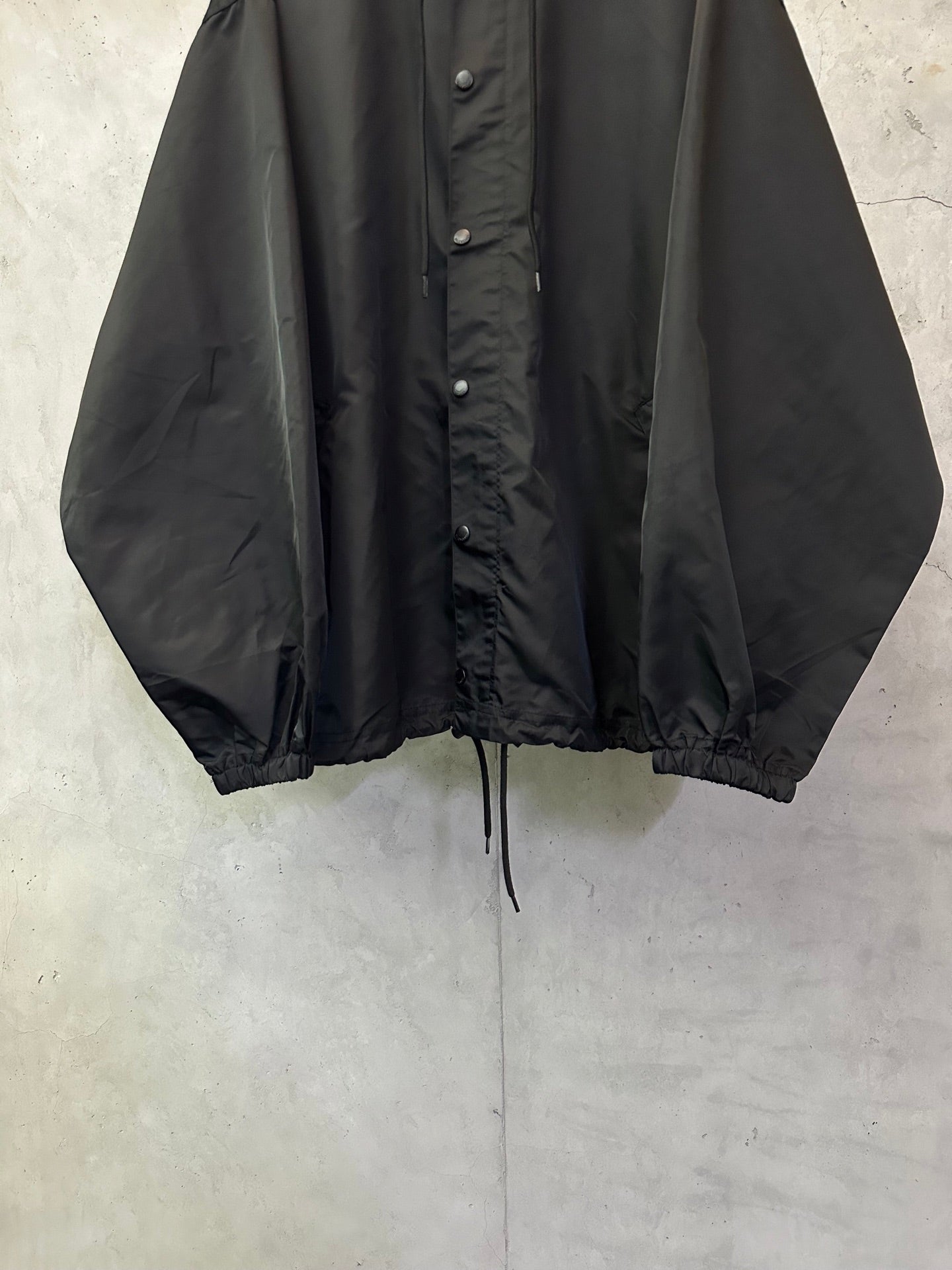 Black hooded jacket front view with button placket and drawstring waist
