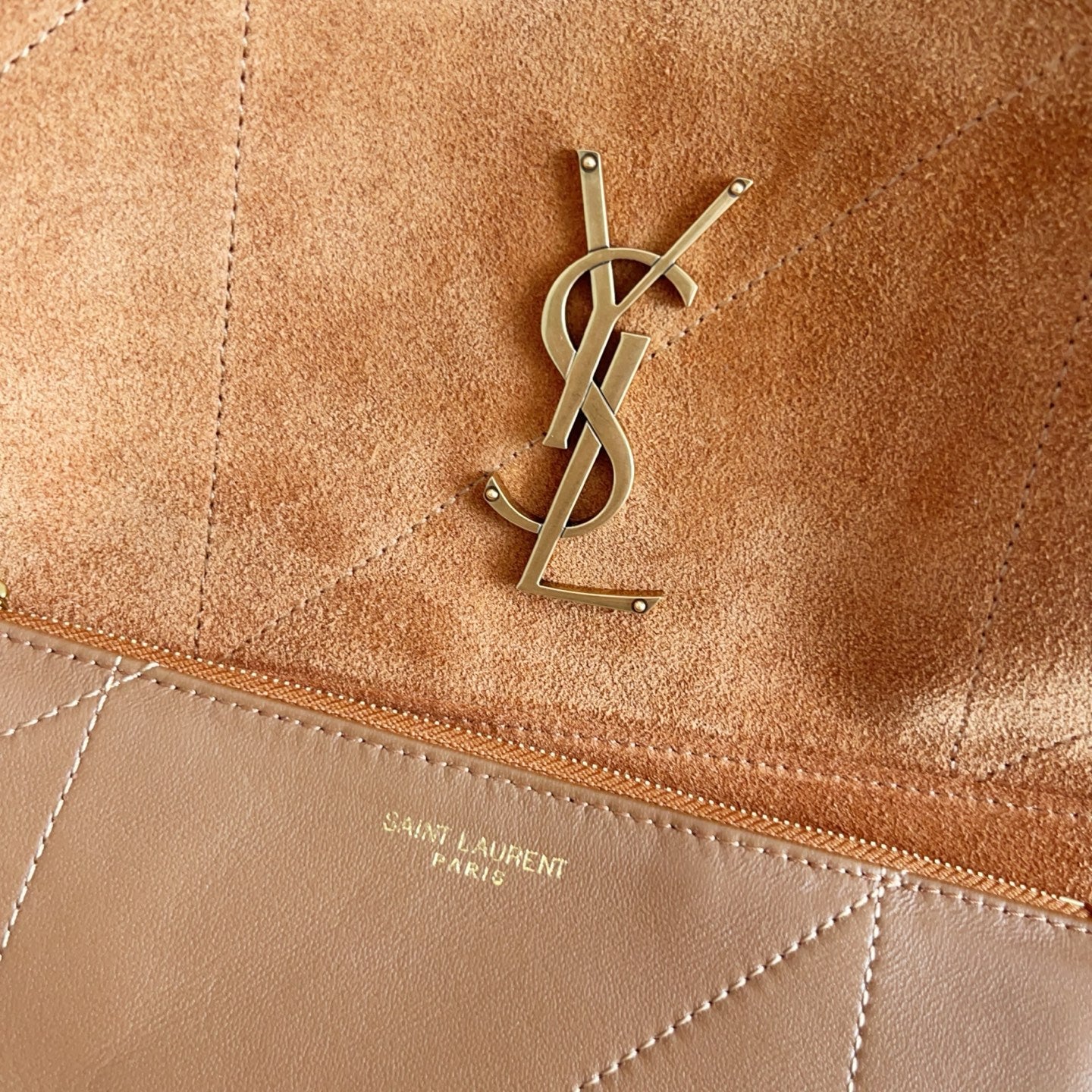 YSL suede pouch close-up with stitched trim and metal YSL logo hardware