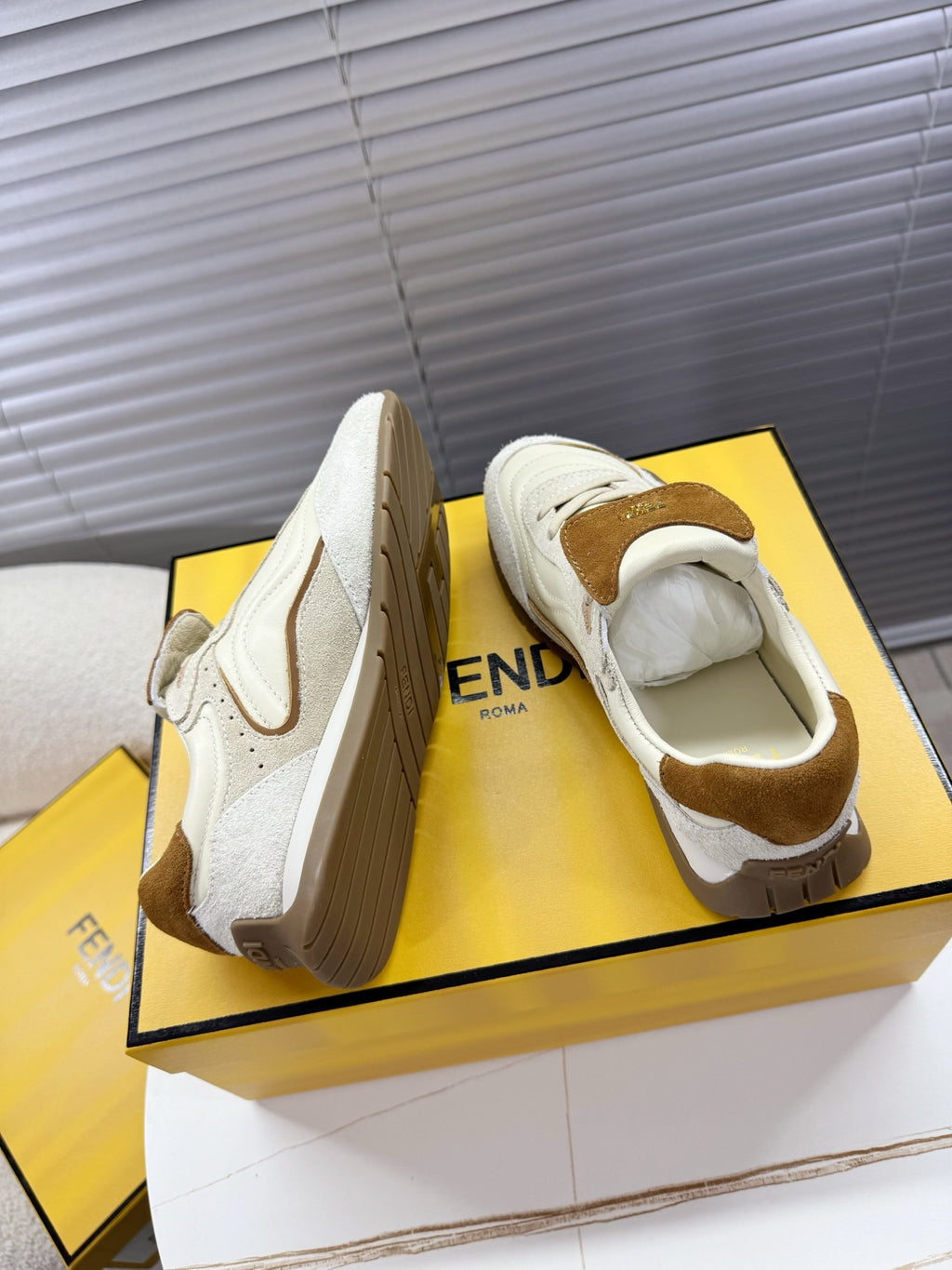 Pair of white low-top sneakers with brown suede heel accents and lace-up design
