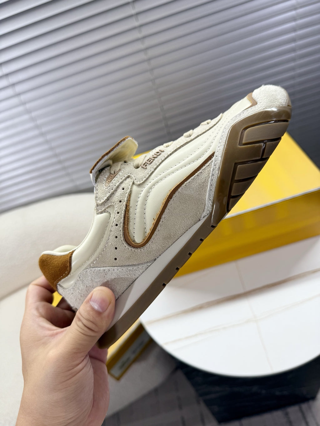 White low-top sneaker viewed from side with brown suede panels and tread sole