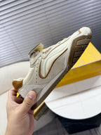 White low-top sneaker viewed from side with brown suede panels and tread sole