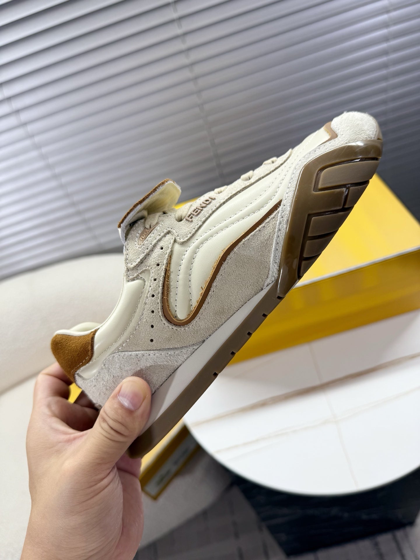 White low-top sneaker viewed from side with brown suede panels and tread sole
