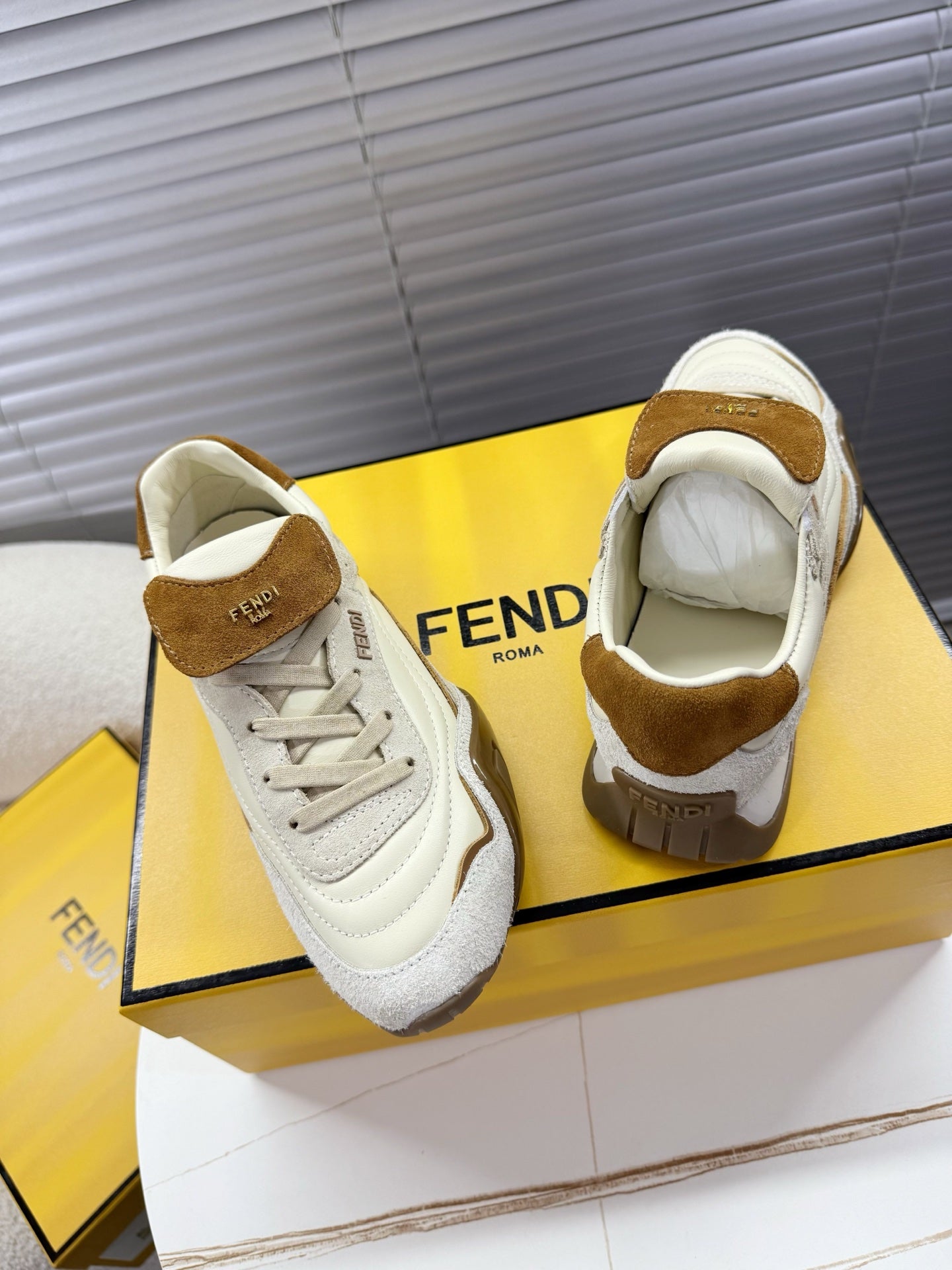 White low-top sneakers with brown suede heel tab and visible tongue label