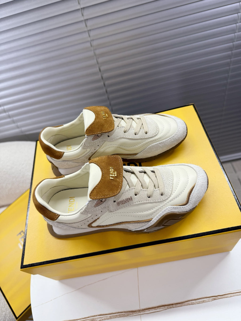 White sneakers with brown suede heel tabs, side vents, and lace-up closure