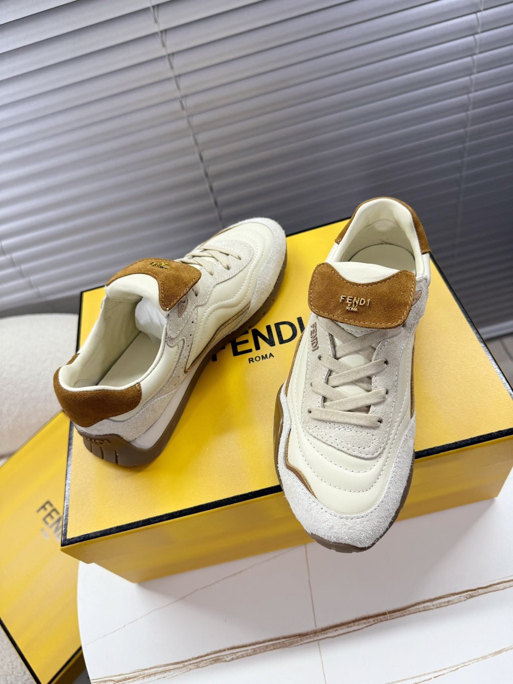 White sneakers with brown suede collar and lace-up front on display box