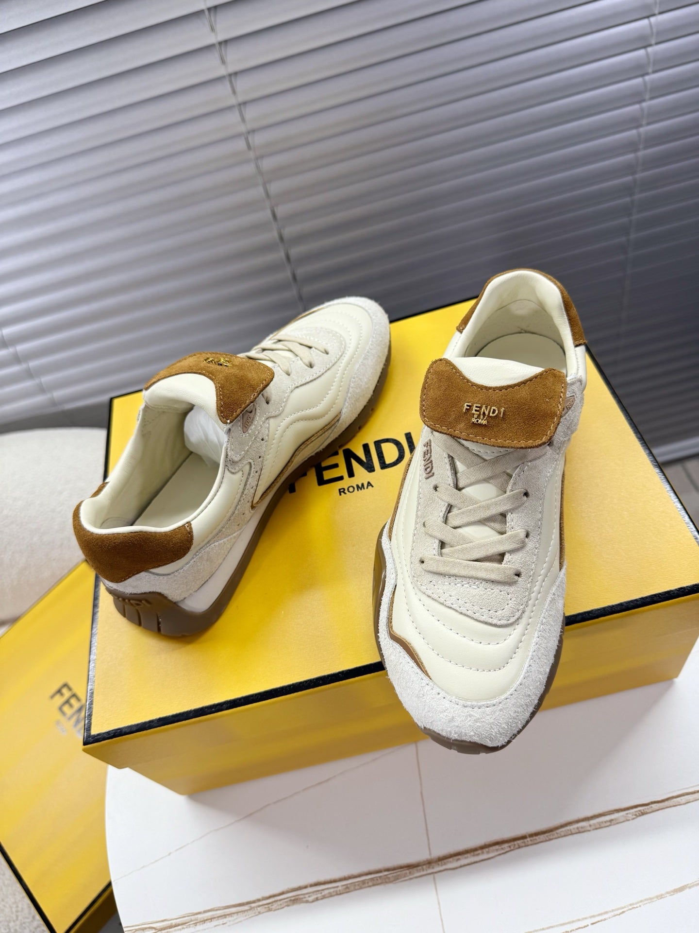White sneakers with brown suede collar and lace-up front on display box