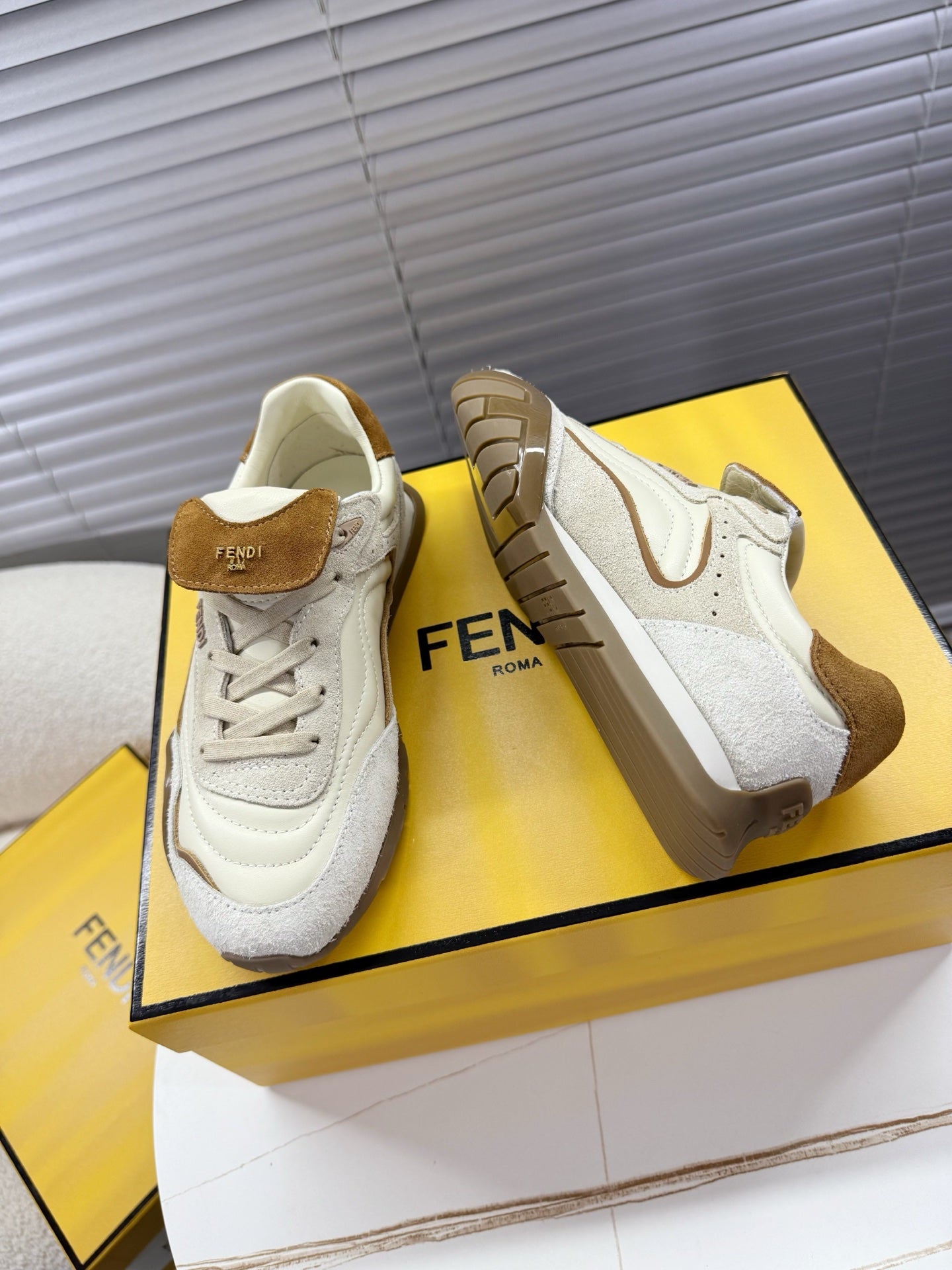 White low-top sneakers with brown suede trim, lace-up front, and FENDI Roma logo