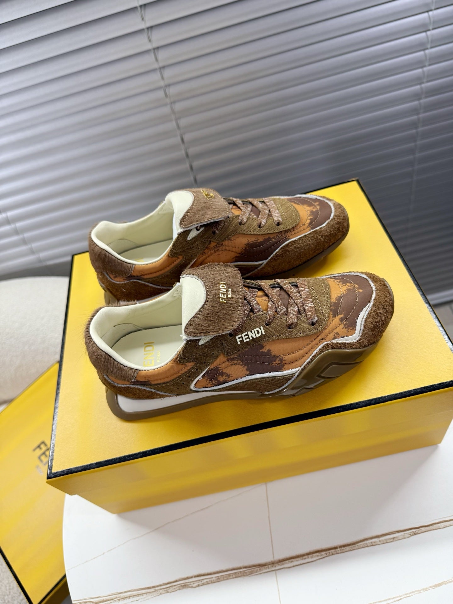 Brown lace-up low-top sneakers with layered panels and cream lining inside